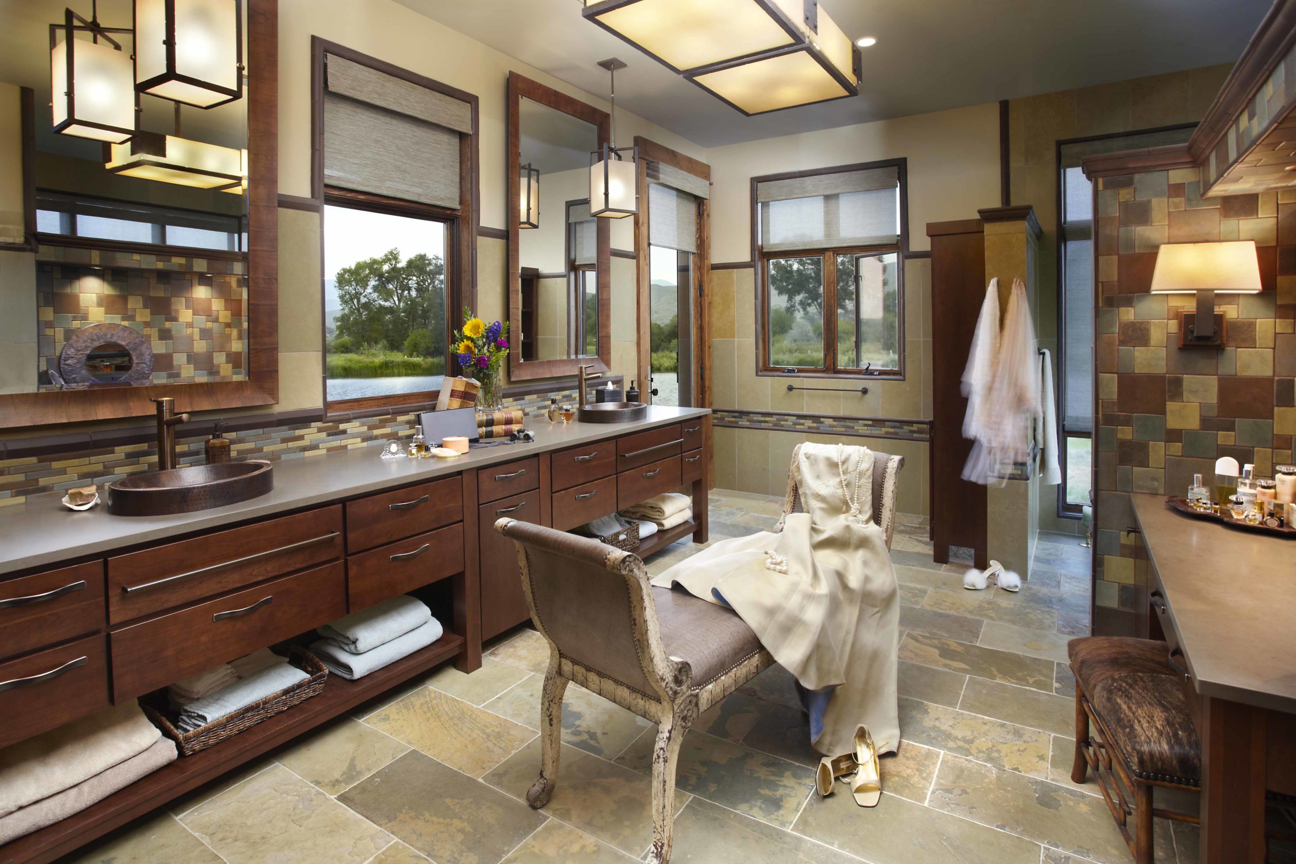 Big bathroom with tiled floors and walls and a long wooden vanity with two sinks