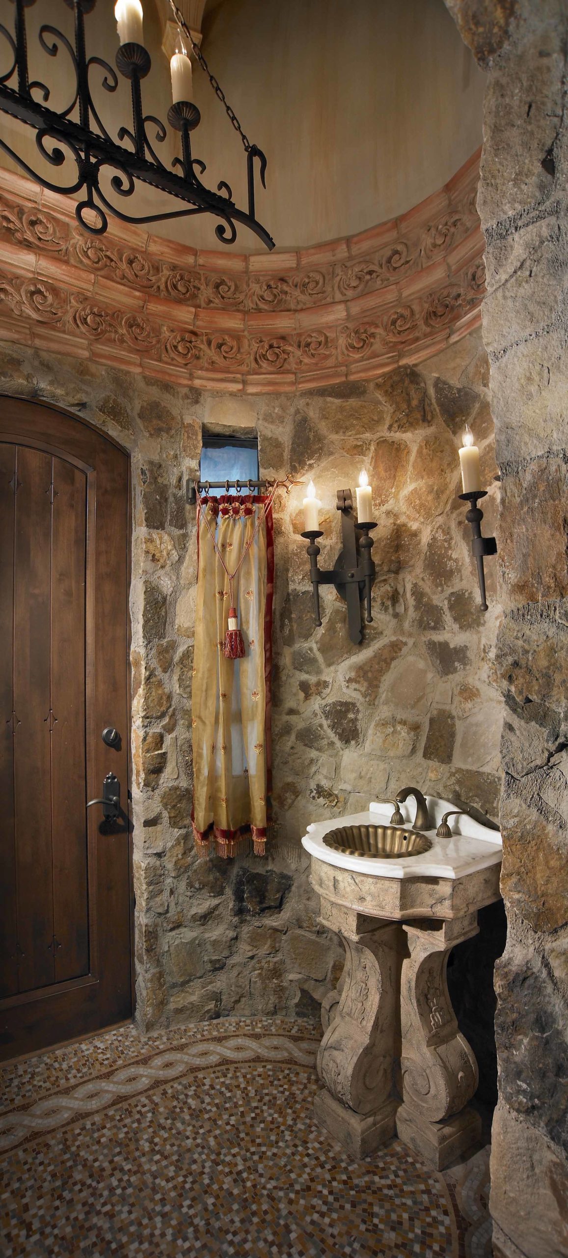 Sink against a stone wall with candles hanging above it
