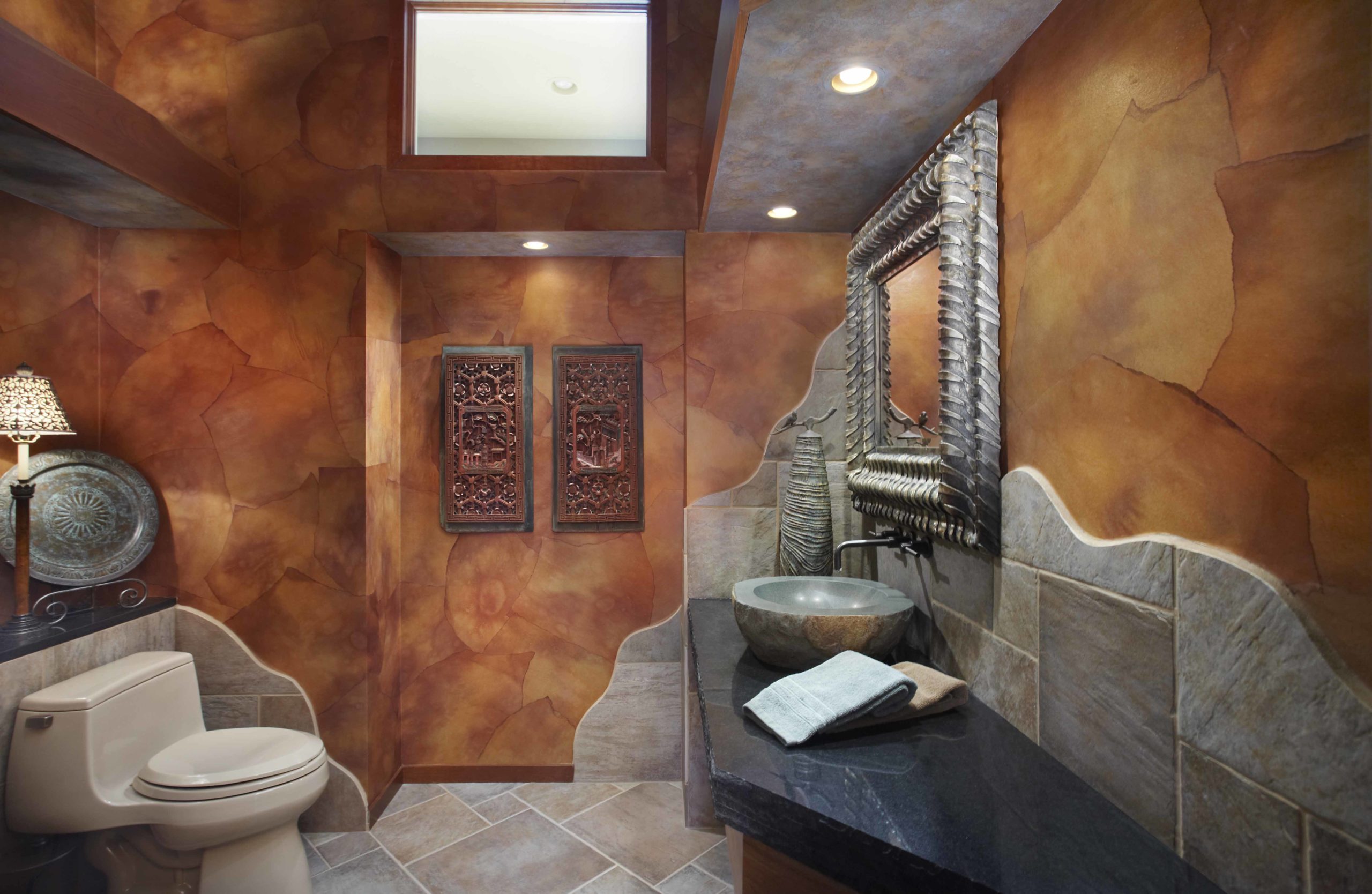 Bathroom with brown stone walls and indigenous art on the walls