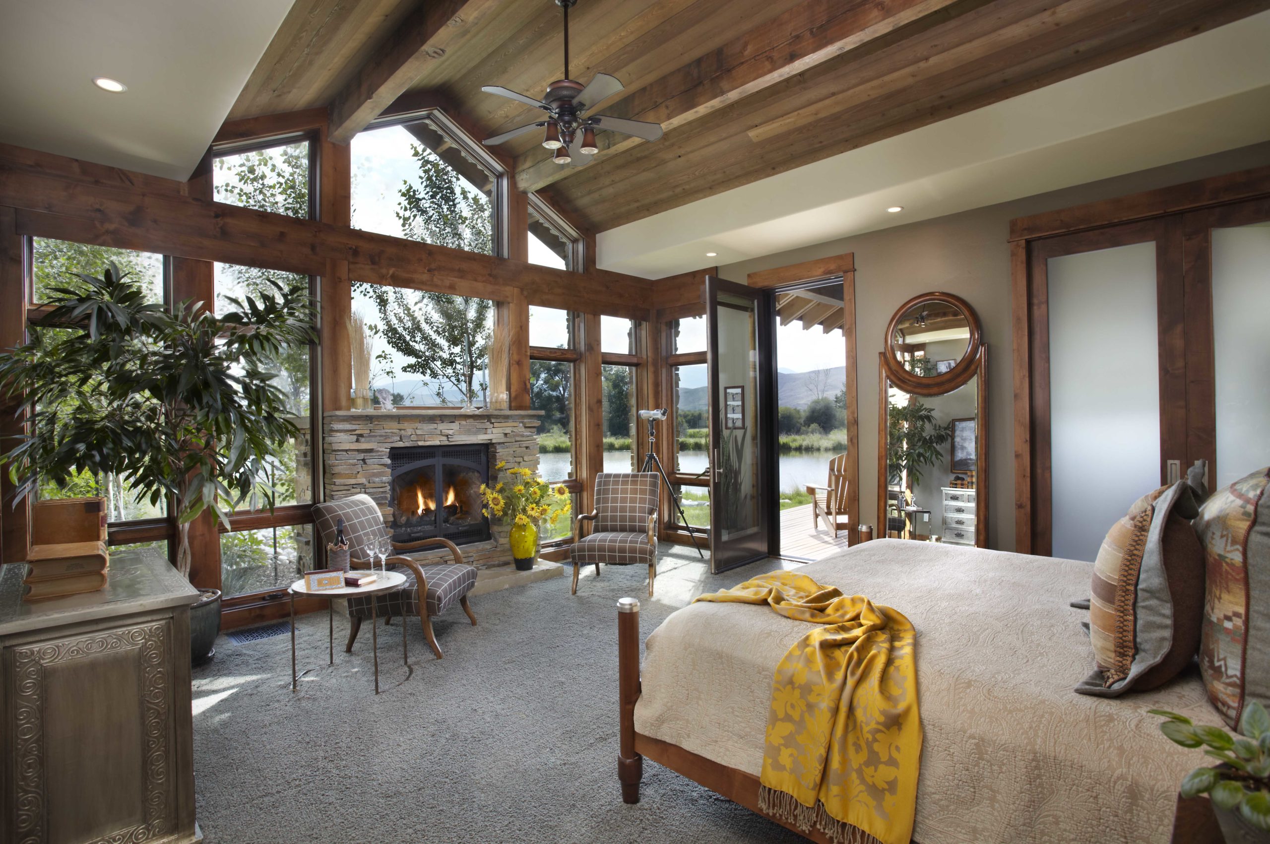 Bedroom with bed facing floor to ceiling windows overlooking a pond