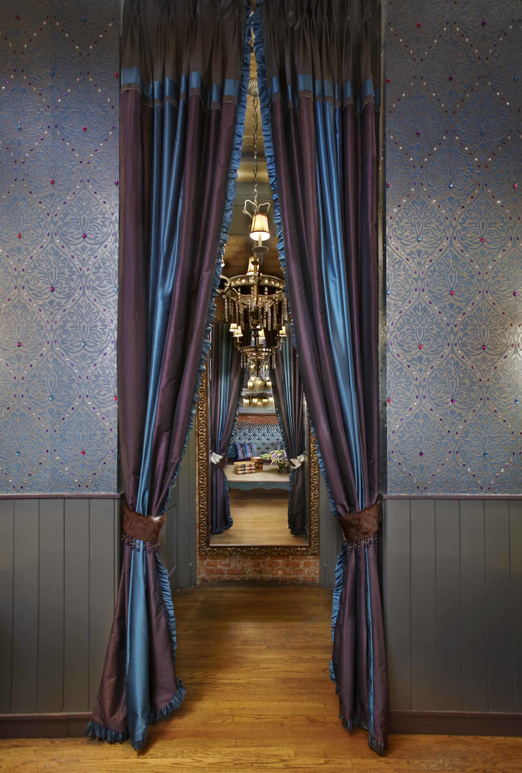 Hallway with a chandelier, mirror, purple drapes and beautiful jeweled wallpaper