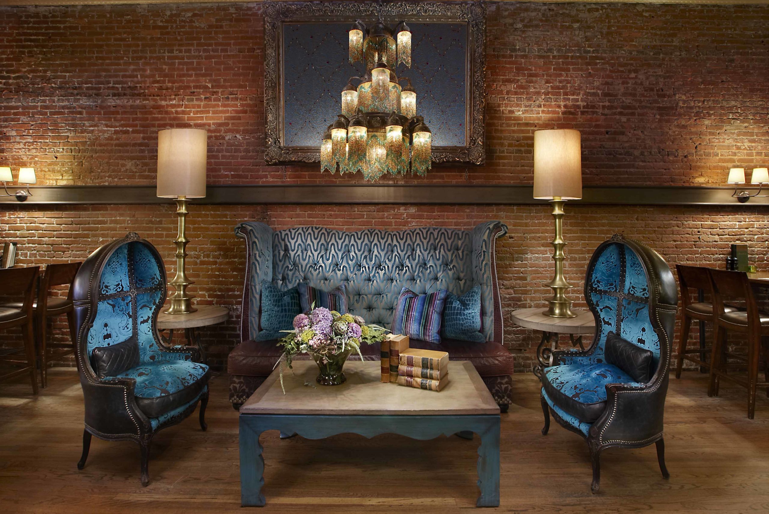 Blue velvet couch and chairs in front of brick wall