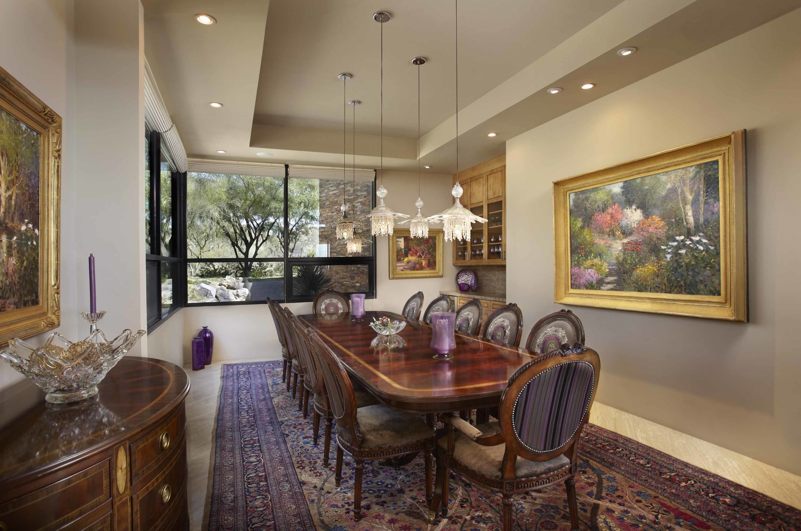 dining room with long table, neutral walls and big paintings hanging on the walls