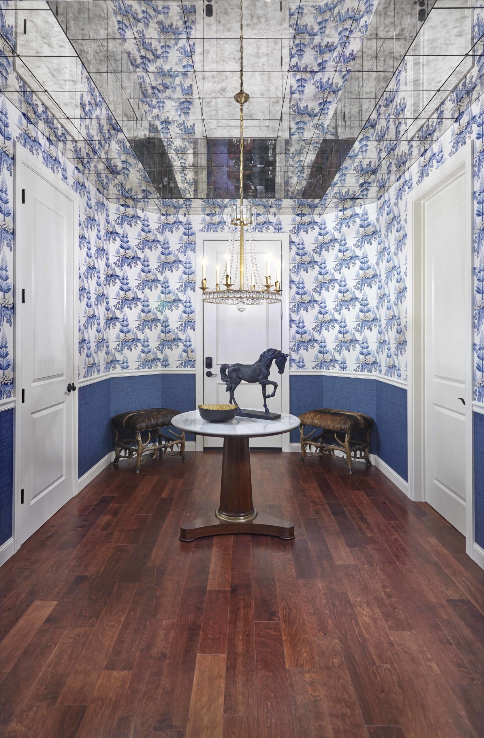 Hallway with blue and white wallpaper on walls, dark wooden floors and a circle console table in the middle