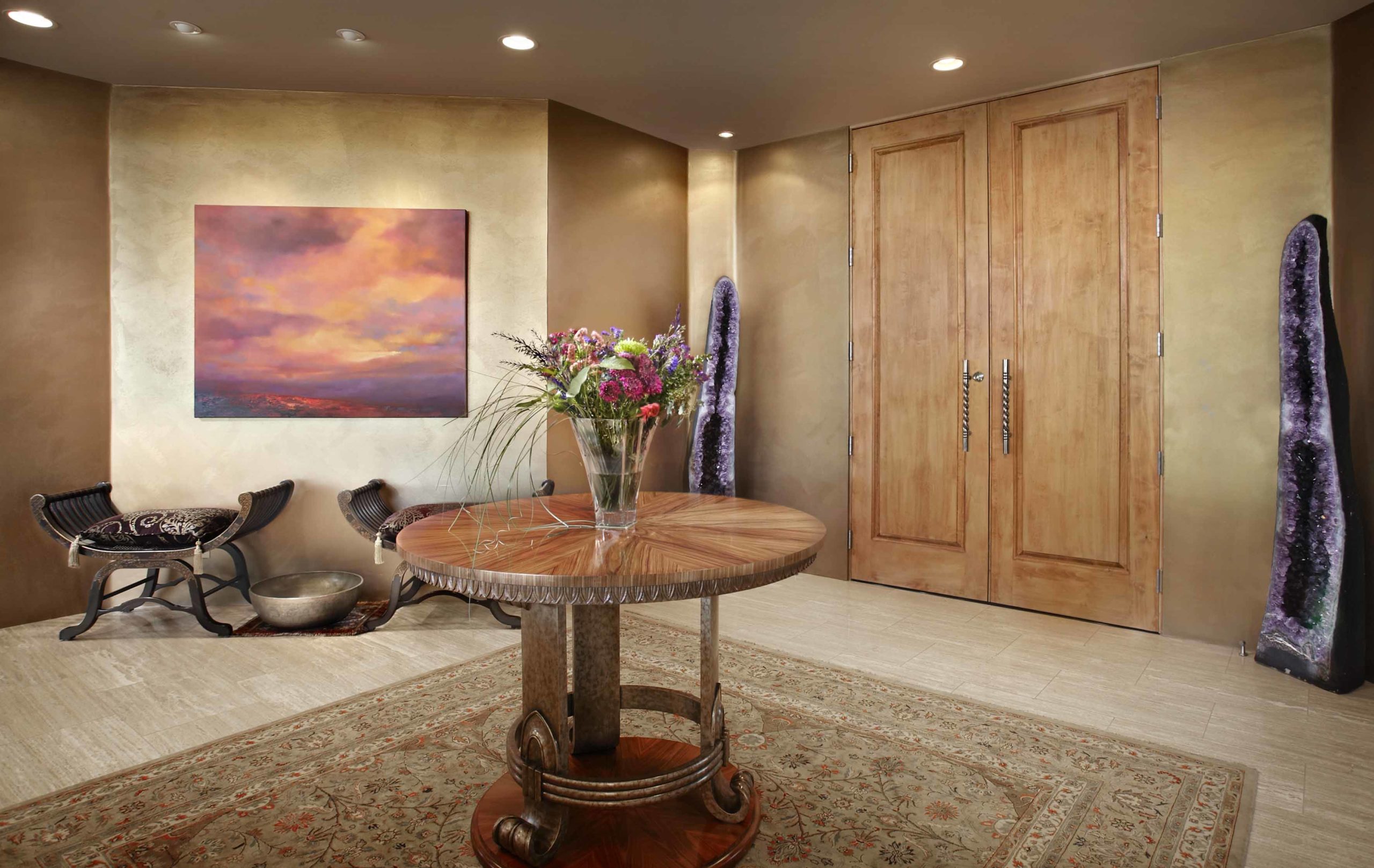 Foyer with a big square rug and a circle wooden table in the middle
