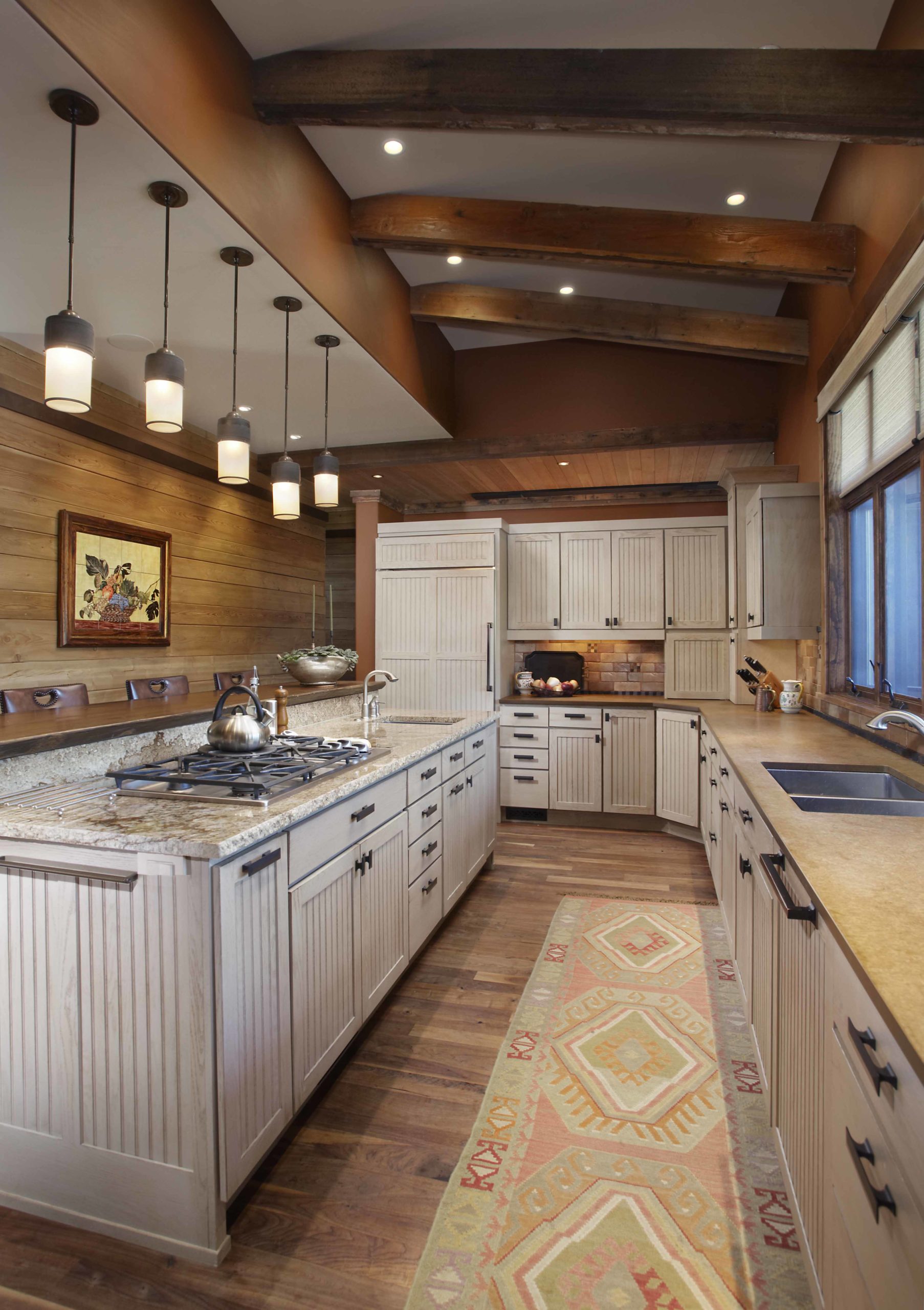 Long kitchen with white washed cabinets and dark wooden beams